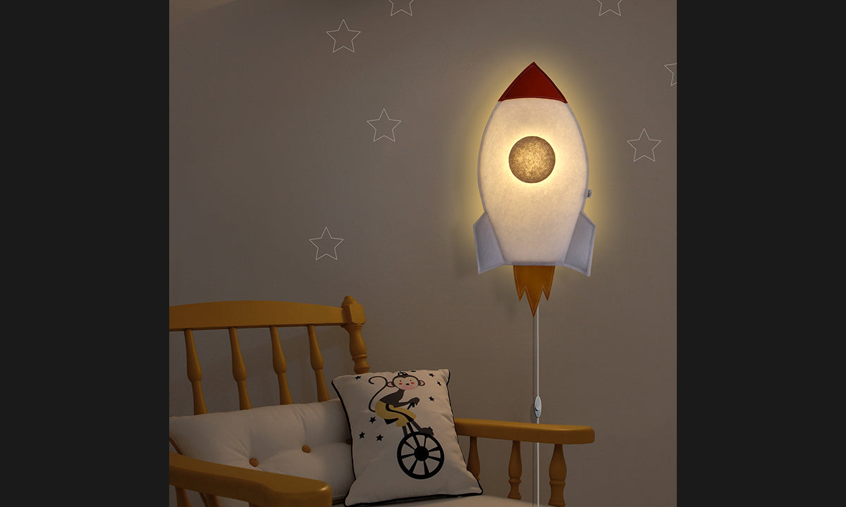 Lámpara cohete de fieltro encendida en la pared de una habitación infantil